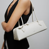 Person holding a white handbag against a plain background