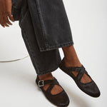Person wearing black shoes and jeans on a white background