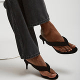 Person wearing black high-heeled sandals with a white background
