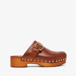 Brown leather clog shoe with gold buckle and studs on a white background