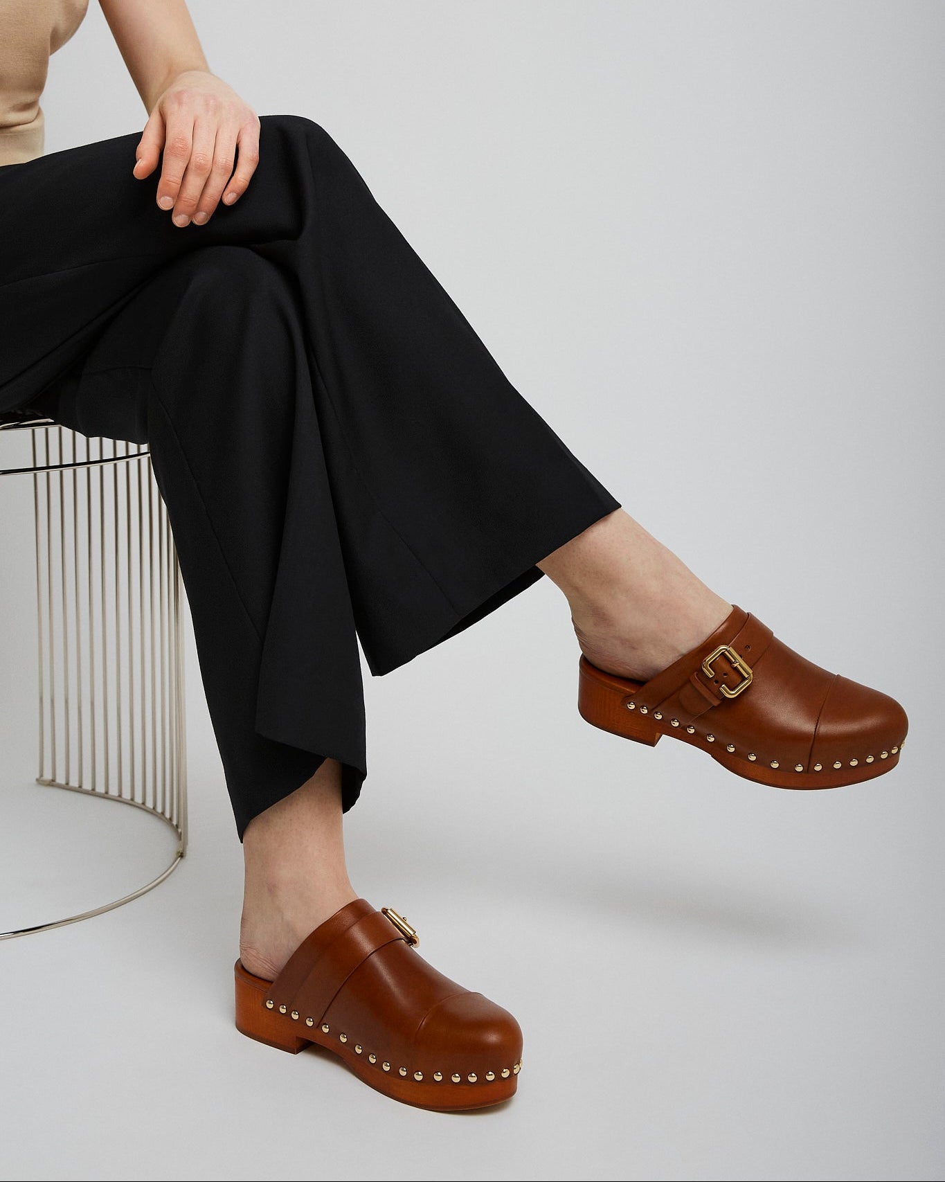 Person wearing brown clogs with a neutral background