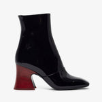 Black patent leather ankle boot with a red heel on a white background