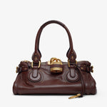 Brown leather handbag with gold accents on a white background