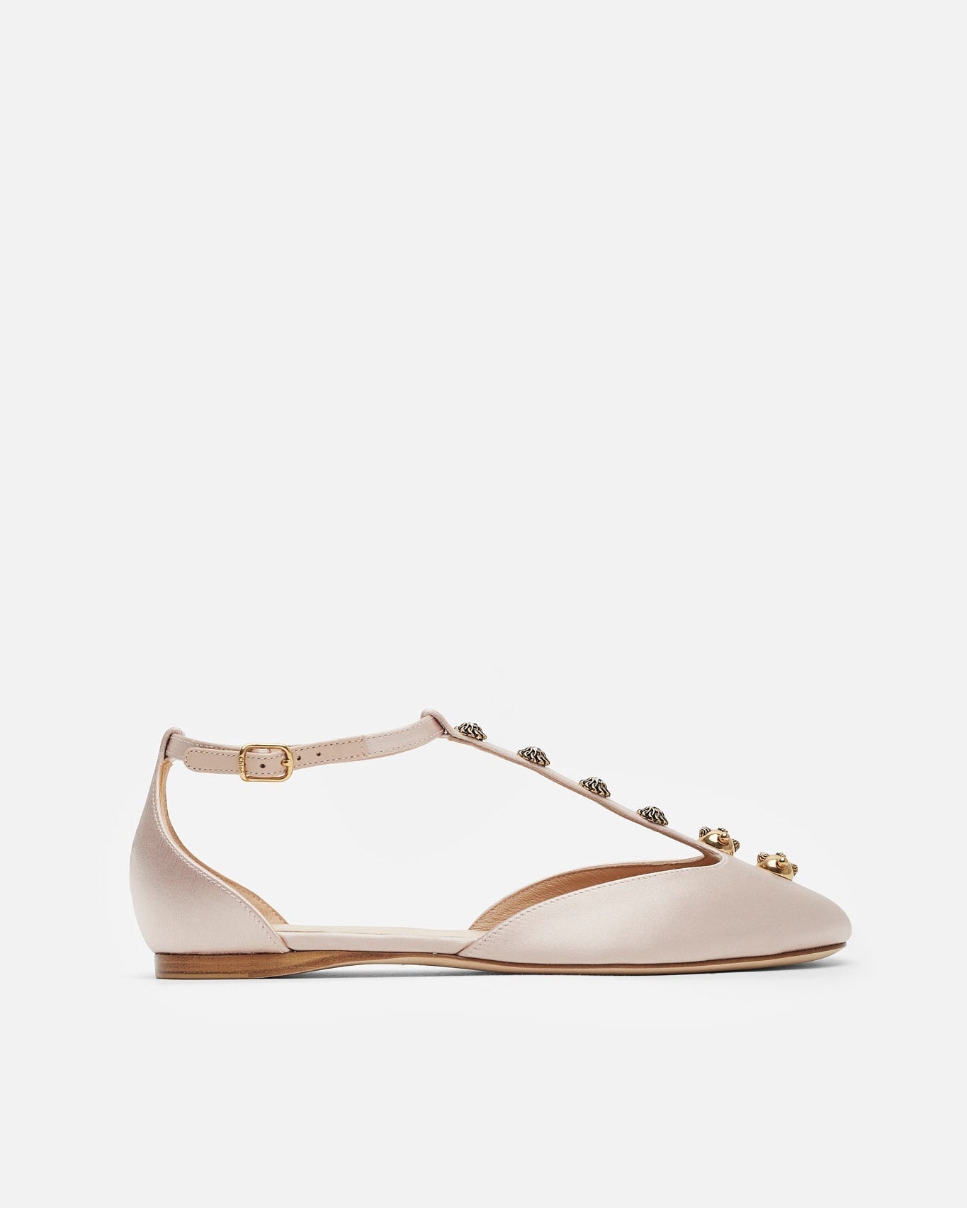 Beige flat shoe with decorative straps on a white background