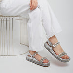 Person wearing silver sandals with a neutral background