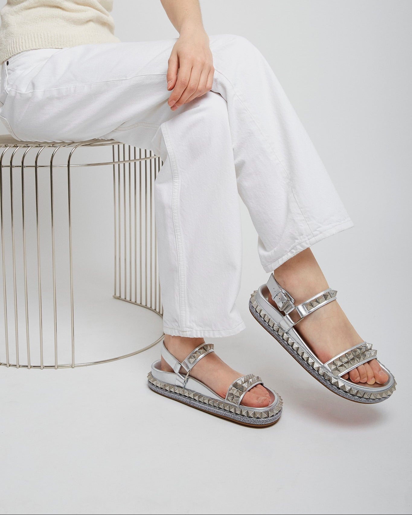 Person wearing silver sandals with a neutral background