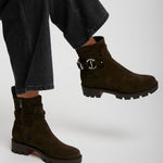 Brown suede ankle boots worn with black jeans on a white background