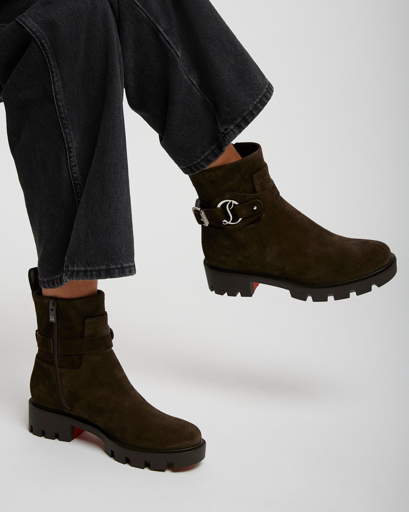 Brown suede ankle boots worn with black jeans on a white background