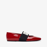 Red patent leather flat shoe with a black strap on a white background