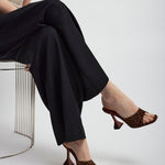 Person wearing black pants and leopard print high heels on a white background