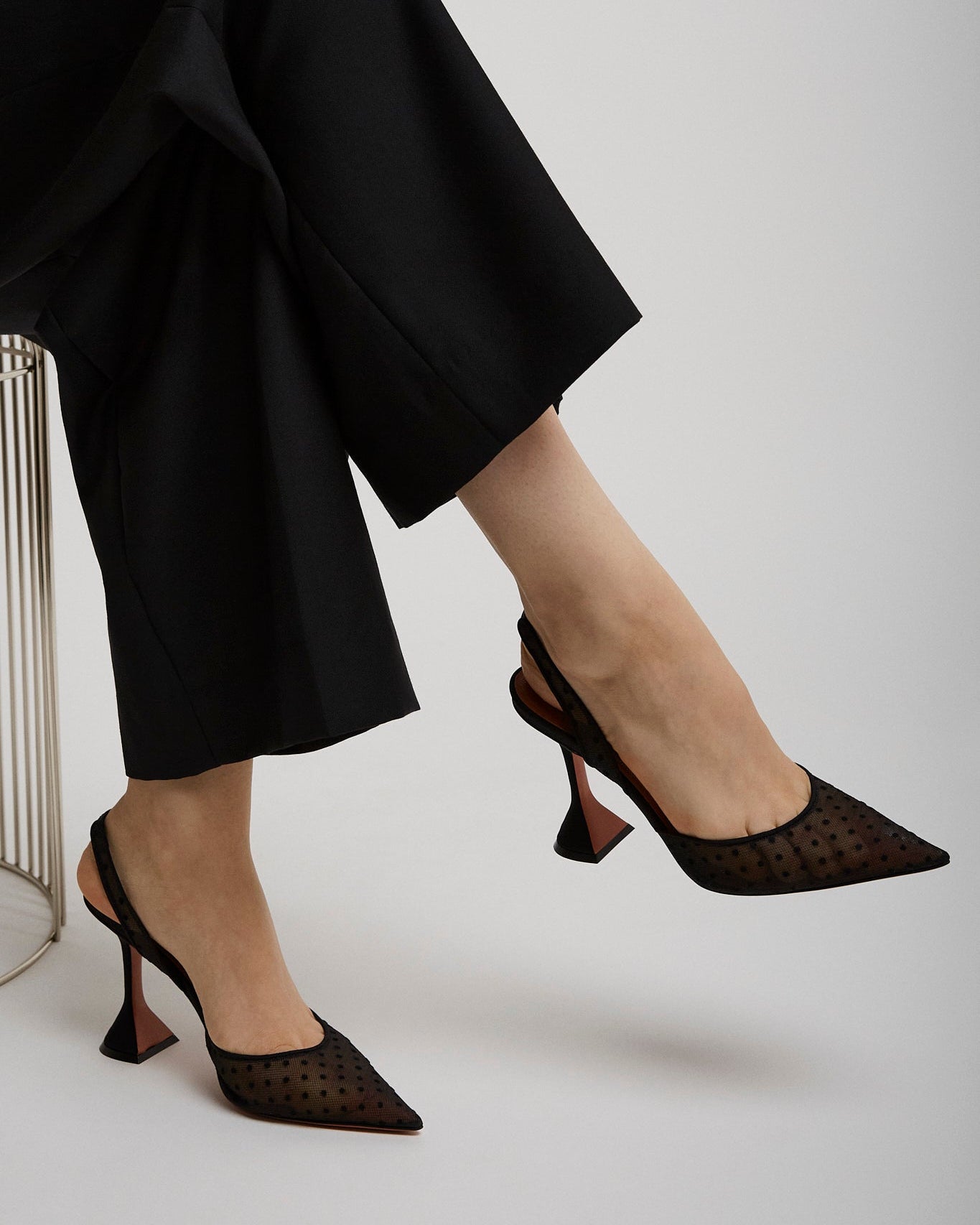 Person wearing black high-heeled shoes with a white background