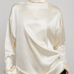 Person wearing a cream-colored long-sleeve top against a gray background