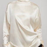 Person wearing a cream-colored long-sleeve top against a gray background