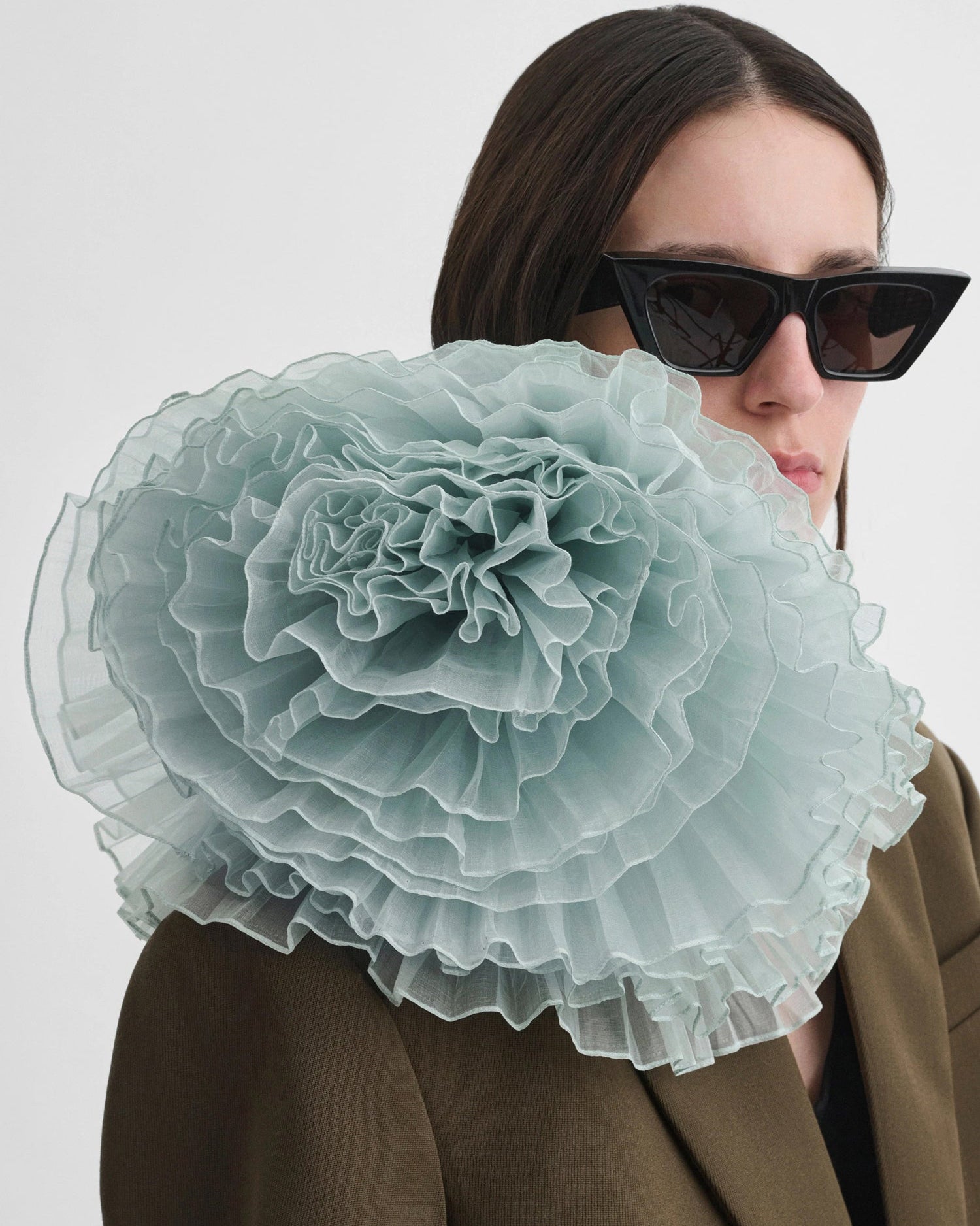 Person wearing a large light blue floral accessory on a white background