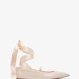 Beige ballerina shoes with ribbon straps on a white background