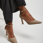 Brown high-heeled shoes worn with black pants on a white background